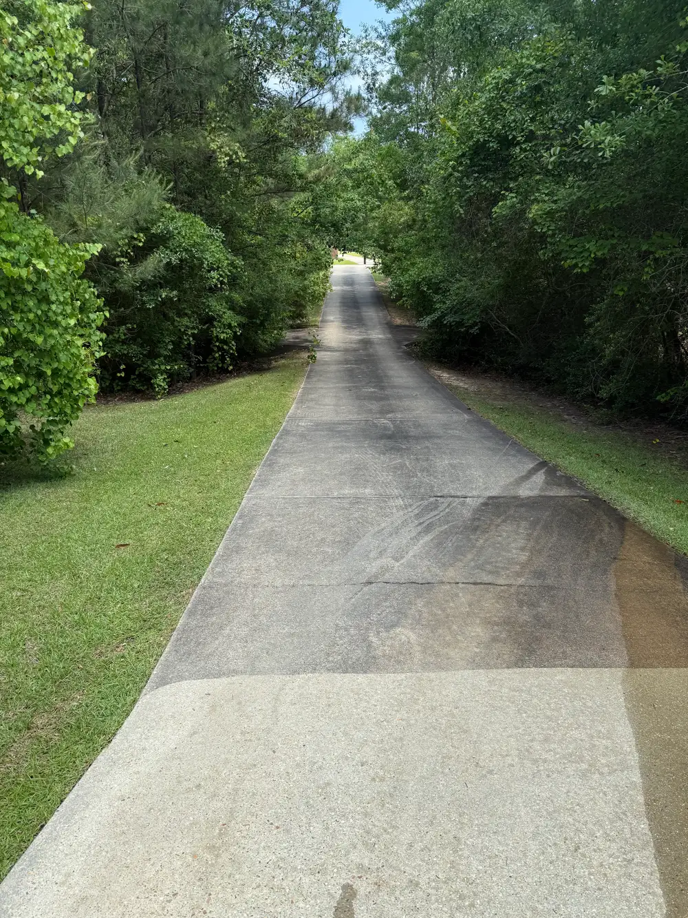 Long concrete driveway half cleaned, showing the dark dirty section next to the clean section